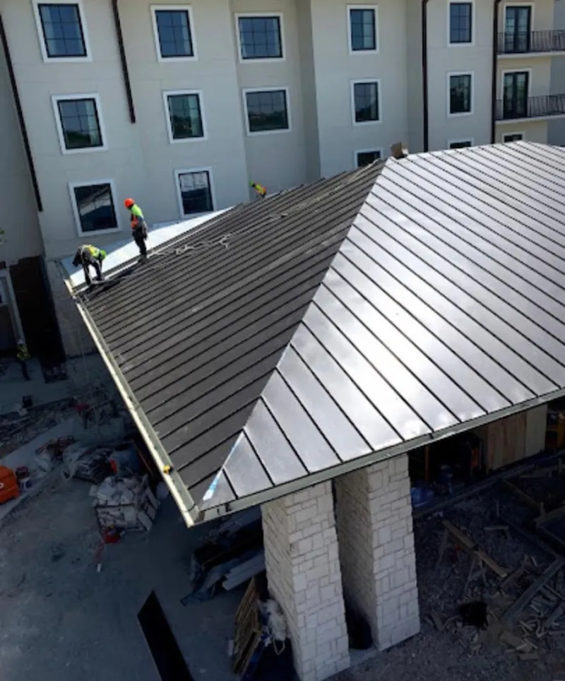 Crew installing standing seam metal roof panels on a commercial project in Pleasanton